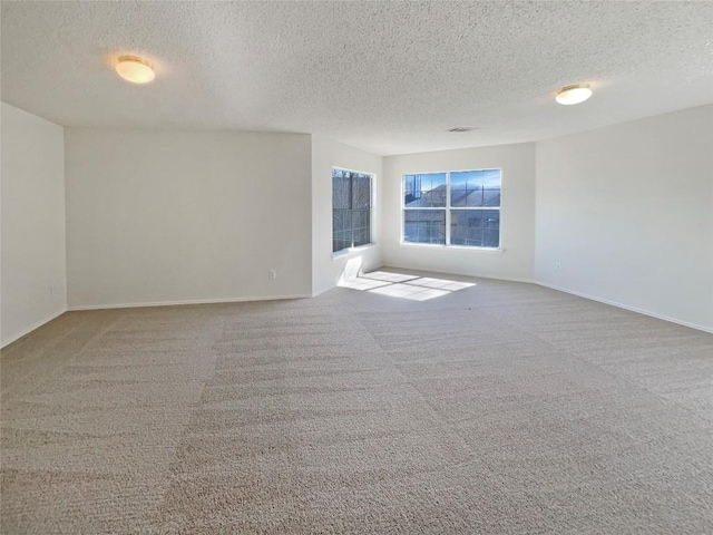 carpeted empty room with visible vents, a textured ceiling, and baseboards