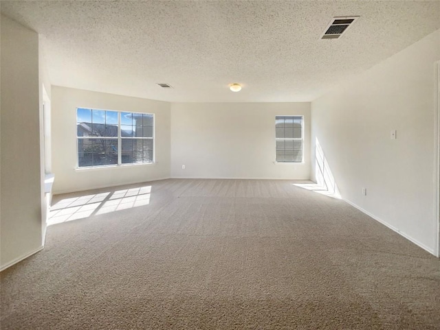 spare room with a textured ceiling, carpet, and visible vents