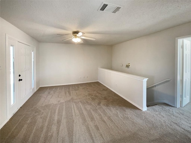 empty room featuring a textured ceiling, carpet flooring, and visible vents