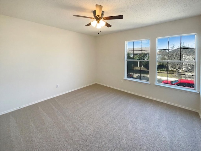 empty room featuring a textured ceiling, carpet floors, ceiling fan, and baseboards