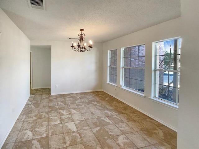 spare room with an inviting chandelier, baseboards, visible vents, and a textured ceiling