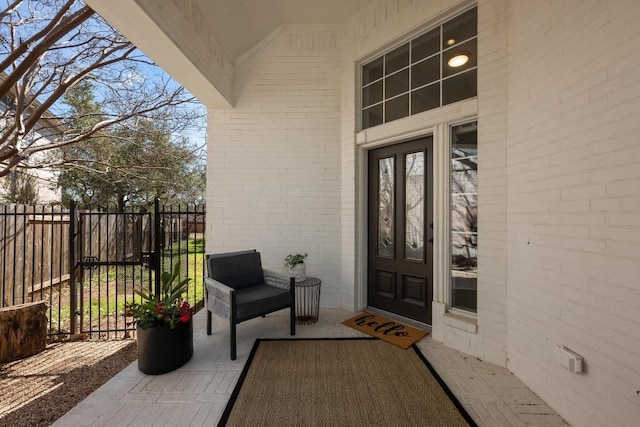 view of exterior entry with brick siding and fence