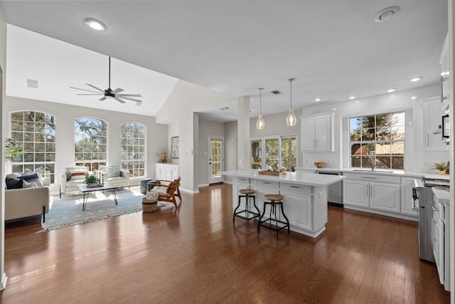 kitchen featuring a kitchen island, open floor plan, stainless steel appliances, light countertops, and white cabinetry