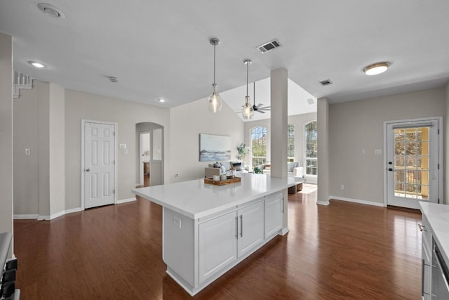 kitchen with dark wood-type flooring, visible vents, light countertops, and arched walkways