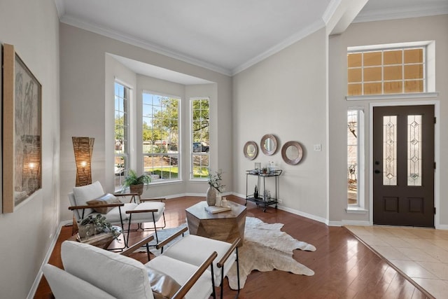 interior space featuring crown molding, a high ceiling, baseboards, and wood finished floors