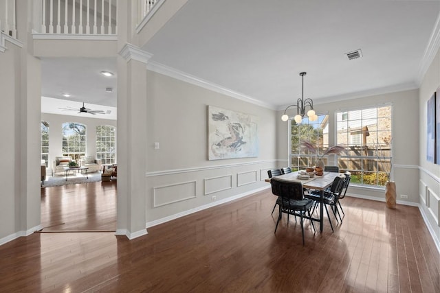 dining room featuring crown molding, wood finished floors, visible vents, and ornate columns