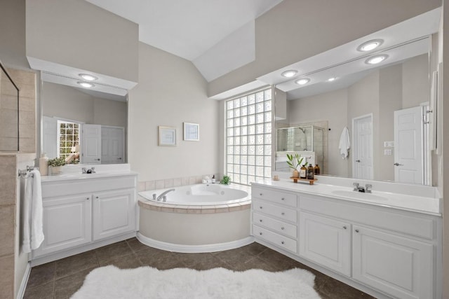 bathroom with lofted ceiling, two vanities, a stall shower, a sink, and a bath