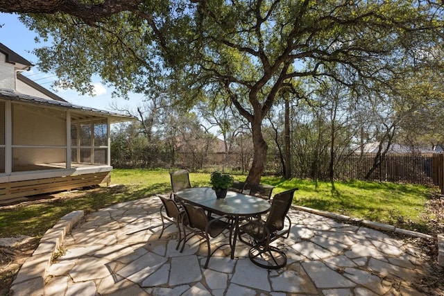 view of patio featuring a sunroom, outdoor dining area, and a fenced backyard