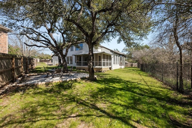 view of yard featuring a sunroom, a fenced backyard, and a patio