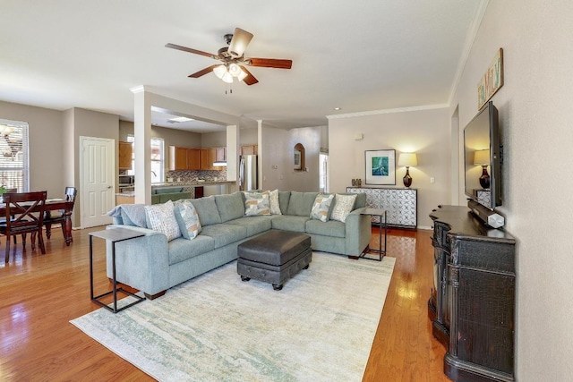 living area featuring crown molding, light wood-style flooring, and ceiling fan