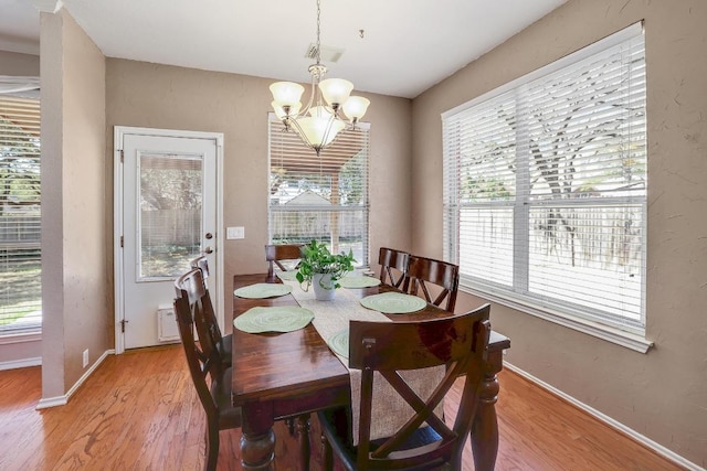 dining room featuring a chandelier, light wood-type flooring, and baseboards