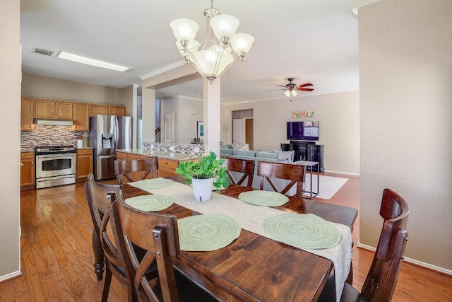 dining room featuring crown molding, visible vents, wood finished floors, and ceiling fan with notable chandelier