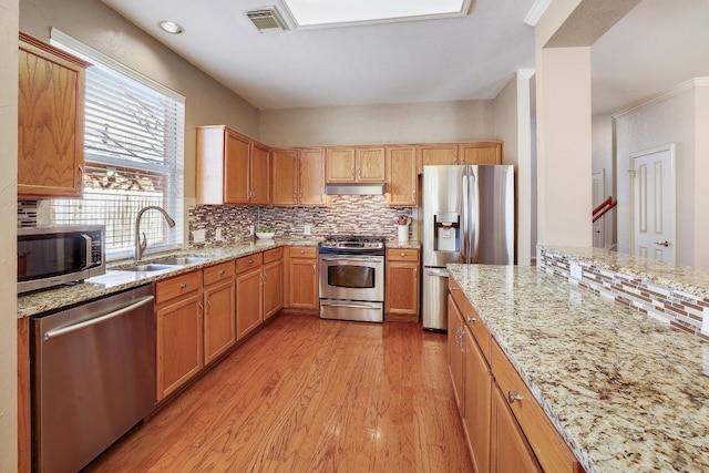 kitchen featuring a sink, visible vents, light wood-style floors, appliances with stainless steel finishes, and decorative backsplash