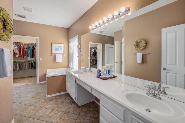 bathroom featuring a spacious closet, double vanity, a sink, and tile patterned floors