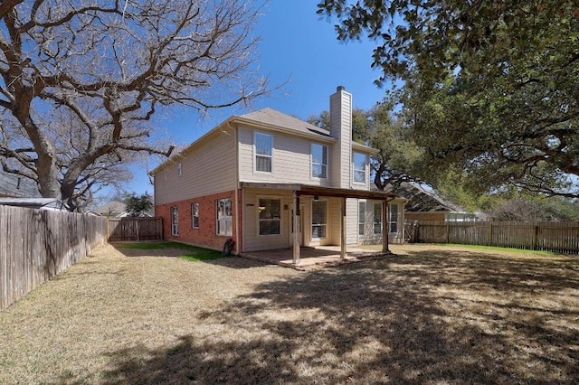 rear view of house with a fenced backyard, a chimney, a yard, a patio area, and brick siding