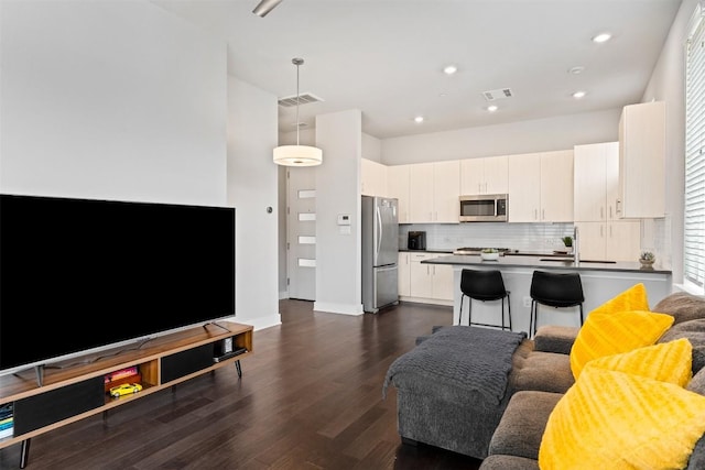 living area with dark wood-style flooring, visible vents, and recessed lighting