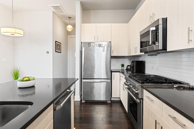 kitchen with visible vents, dark wood finished floors, dark countertops, stainless steel appliances, and backsplash