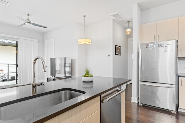 kitchen with stainless steel appliances, dark wood-style flooring, a sink, visible vents, and dark countertops