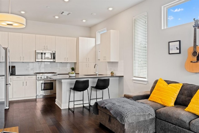 kitchen with visible vents, appliances with stainless steel finishes, open floor plan, a peninsula, and a healthy amount of sunlight