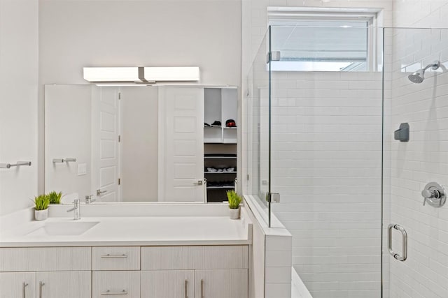 bathroom with a walk in closet, a shower stall, and vanity