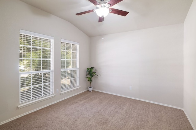 carpeted spare room featuring vaulted ceiling, baseboards, and ceiling fan