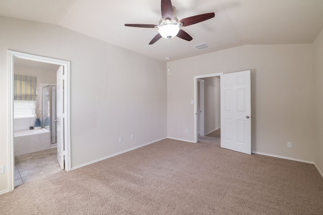 unfurnished bedroom featuring light colored carpet, visible vents, vaulted ceiling, and baseboards