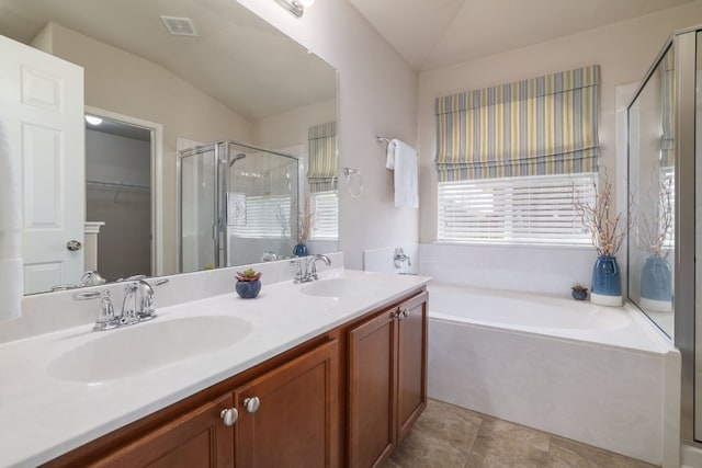 full bathroom with a bath, a stall shower, vaulted ceiling, and a sink