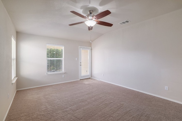 carpeted spare room with visible vents, baseboards, vaulted ceiling, and a ceiling fan