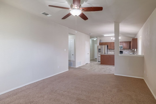 unfurnished living room with visible vents, vaulted ceiling, light carpet, and baseboards