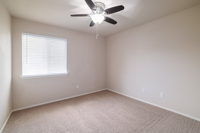 carpeted empty room with a ceiling fan and baseboards