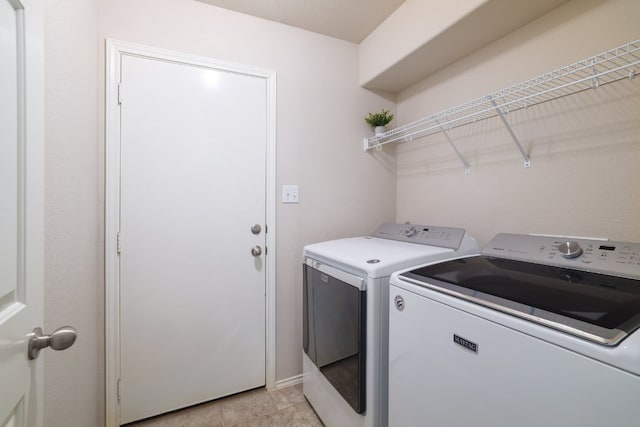 laundry area with laundry area, washing machine and clothes dryer, and light tile patterned floors