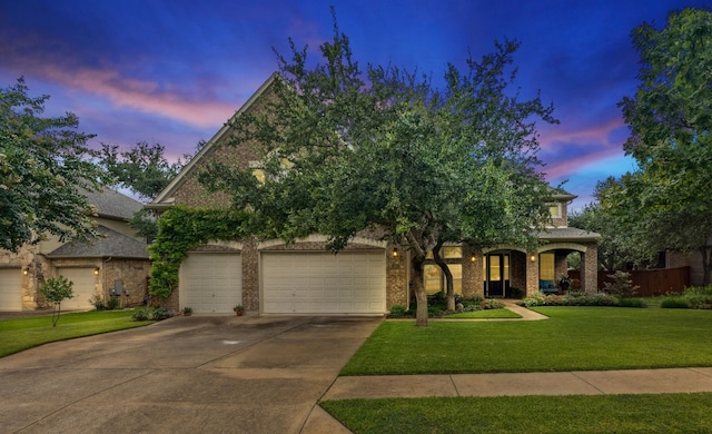 view of front of house with a garage, concrete driveway, brick siding, and a yard