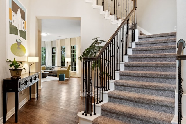 stairs featuring wood finished floors and a towering ceiling