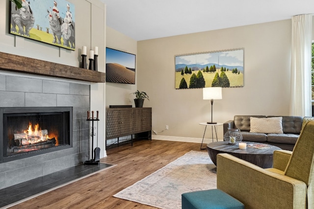 living room featuring a fireplace, baseboards, and wood finished floors