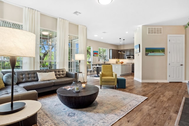 living room with recessed lighting, wood finished floors, visible vents, and baseboards