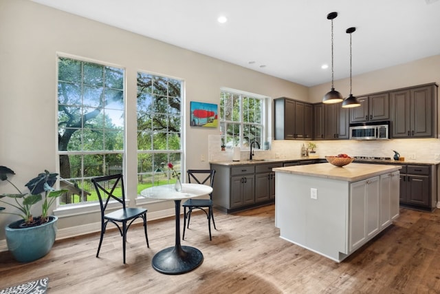 kitchen with light countertops, stainless steel microwave, a sink, and backsplash