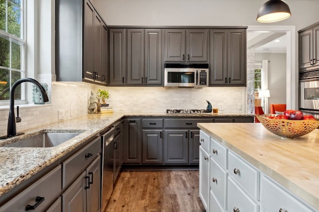 kitchen featuring tasteful backsplash, butcher block counters, wood finished floors, stainless steel appliances, and a sink