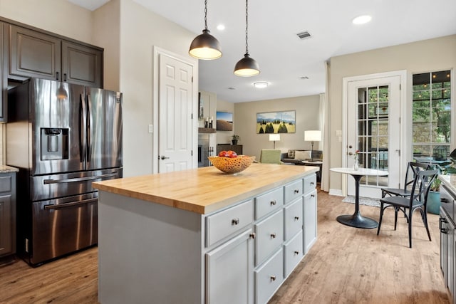 kitchen featuring a center island, visible vents, light wood-style flooring, wood counters, and stainless steel fridge with ice dispenser