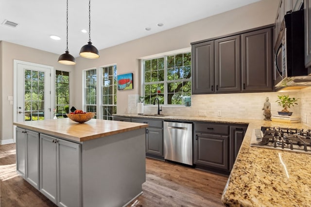 kitchen with a center island, visible vents, appliances with stainless steel finishes, a sink, and wood counters