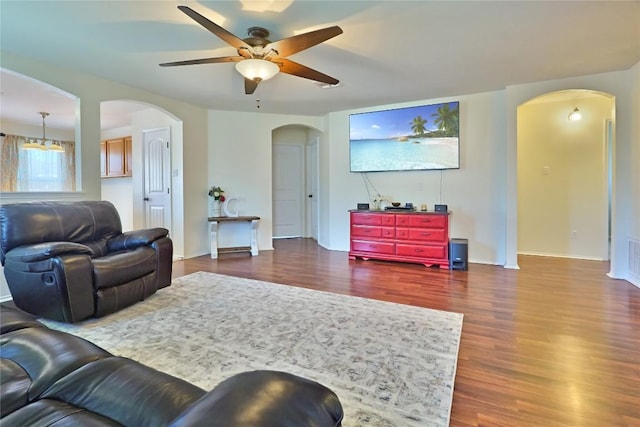 living room with a ceiling fan, arched walkways, dark wood finished floors, and baseboards