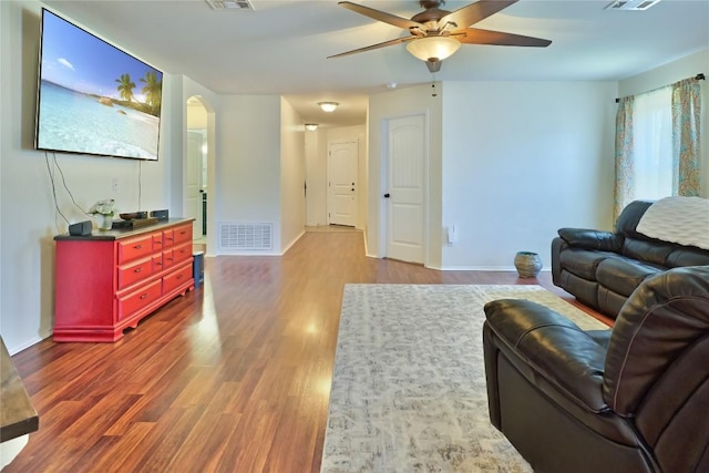 living area featuring baseboards, visible vents, arched walkways, and wood finished floors