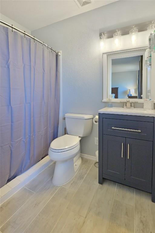 full bath with toilet, vanity, wood finished floors, a shower with curtain, and baseboards