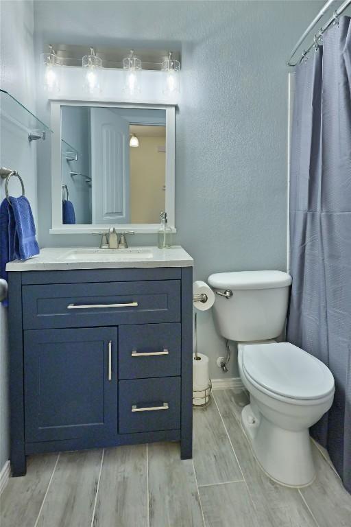 full bathroom featuring toilet, wood finish floors, vanity, baseboards, and a shower with curtain