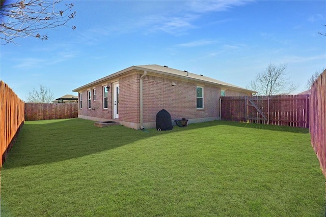 exterior space featuring a yard, brick siding, and a fenced backyard