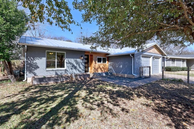 ranch-style house featuring a garage, metal roof, brick siding, and fence