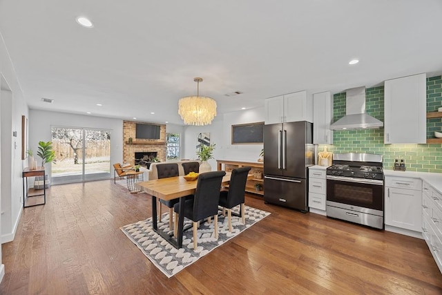 dining space with dark wood-style flooring, a brick fireplace, and recessed lighting