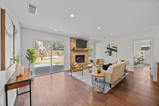 living area with a fireplace, visible vents, wood finished floors, and recessed lighting