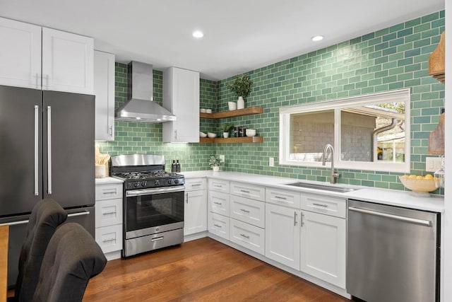 kitchen with wall chimney range hood, stainless steel appliances, a sink, and light countertops