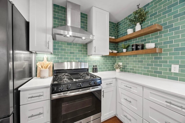 kitchen featuring freestanding refrigerator, stainless steel range with gas stovetop, backsplash, and wall chimney exhaust hood