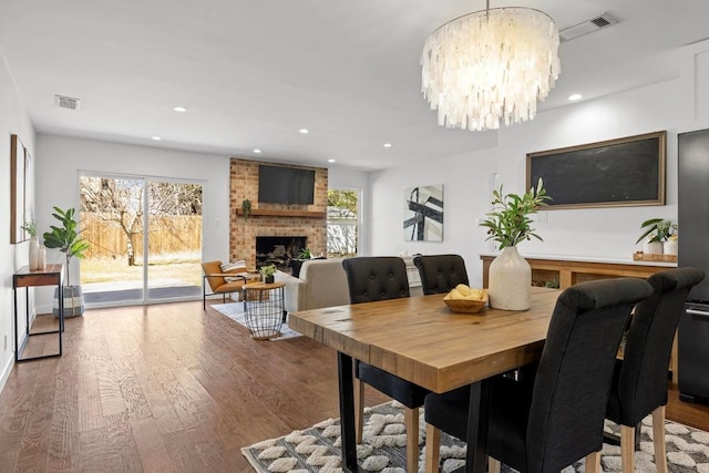 dining space featuring a wealth of natural light, a fireplace, visible vents, and wood finished floors